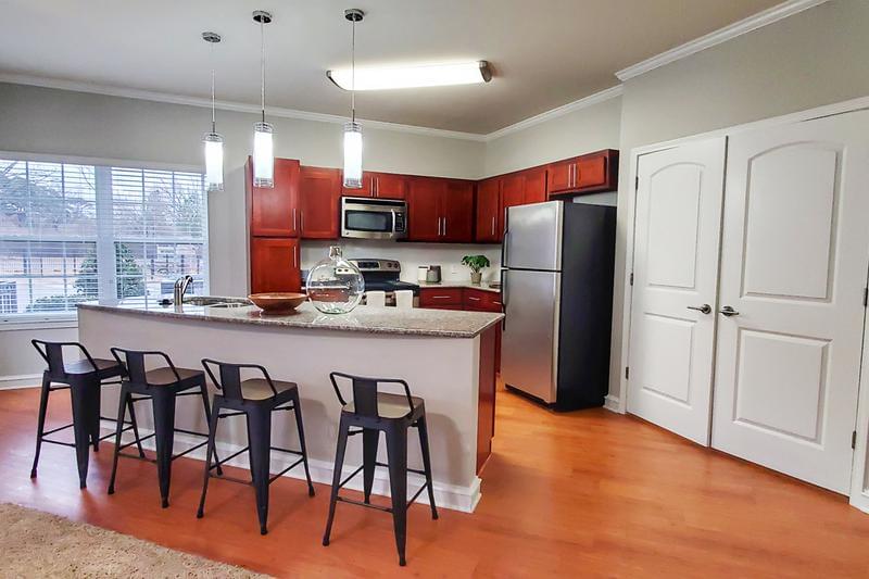 Open Kitchens with Granite Countertops | Our gorgeous open kitchens with cherry wood cabinetry and granite countertops are equipped with stainless steel appliances; microwave, stove, refrigerator and dishwasher.