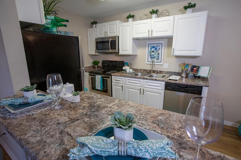 Updated Kitchens | Newly remodeled kitchens featuring white cabinetry, granite-style counter tops, wood-style flooring, and stainless steel appliances.