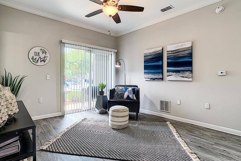 Living Room | Spacious living rooms featuring wood-style flooring, multi-speed ceiling fans, and sliding doors to your private patio.