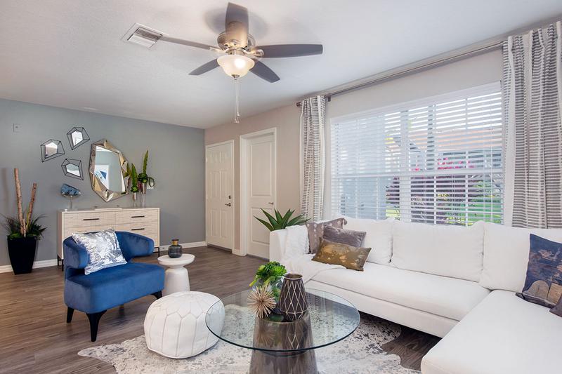 Living Room | Spacious, open living room featuring wood-style flooring, a ceiling fan, and large window.