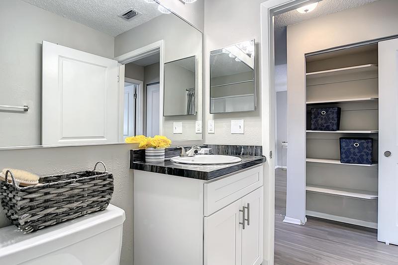 Bathroom | Bathrooms featuring wood-style flooring, black-fusion countertops, and large mirrors.
