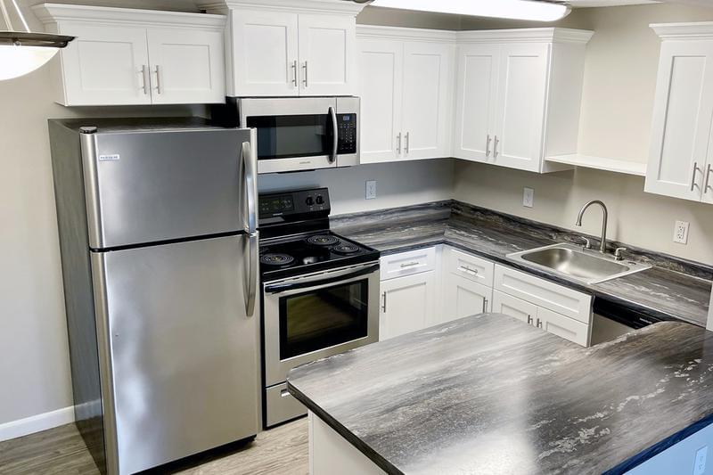 Black Fusion Kitchen | Updated kitchens with black fusion countertops, wood-style flooring, and stainless steel appliances. We are excited to offer in-person tours while following social distancing and we encourage all visitors to wear a face covering.