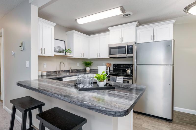 Modern Style Kitchens | Modern kitchens with black fusion countertops, wood-style flooring, and a breakfast bar.