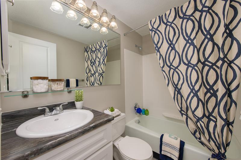 Bathroom | Newly remodeled bathrooms featuring wood-style flooring and black fusion counter tops.