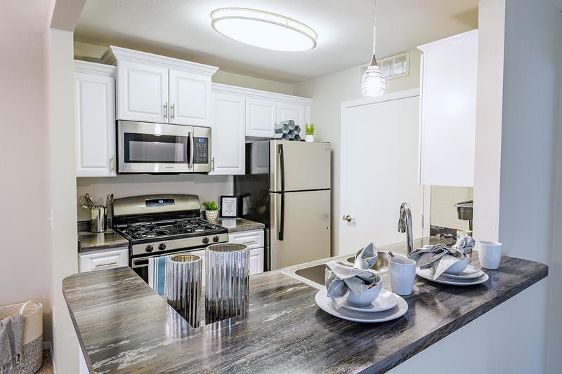 Kitchen | Galley style kitchens featuring stainless steel appliances, black fusion counter tops, wood-style flooring, and a breakfast bar.