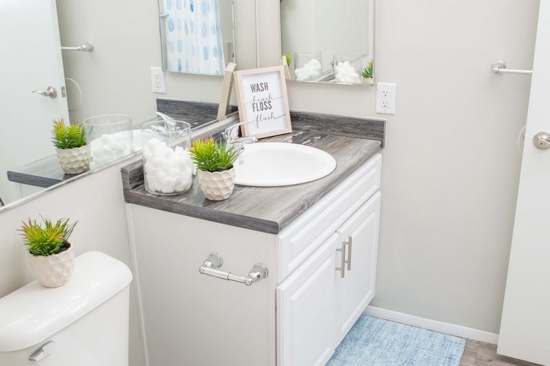 Guest Bathroom | Newly renovated bathrooms featuring black fusion countertops and large mirrors.