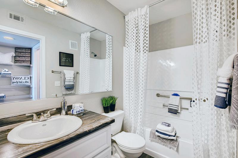 Bathroom | Modern bathrooms feature wood-style flooring, black fusion countertops and large mirrors.