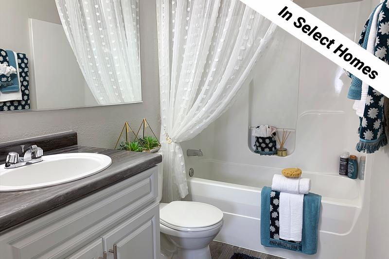 Renovated Bathrooms | Newly renovated bathrooms featuring wood-style flooring, black fusion countertops, and large mirrors.