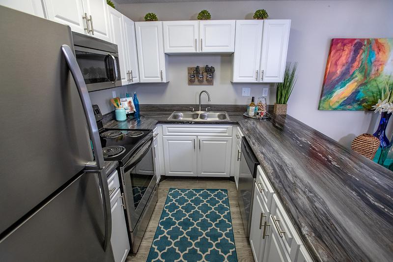 Renovated Kitchens | Newly renovated kitchens featuring wood-style flooring, black fusion countertops, and stainless steel appliances in select homes.