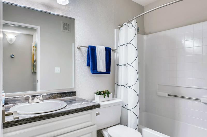 Bathroom | Bathrooms featuring black fusion counter-tops, wood-style flooring, and large mirrors.
