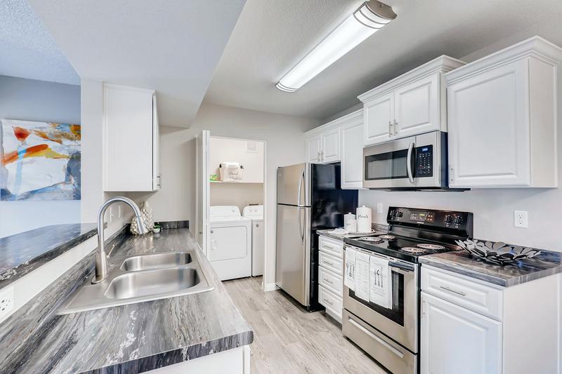 Kitchen | Kitchens featuring black fusion counter-tops, white cabinetry, and stainless steel appliances.