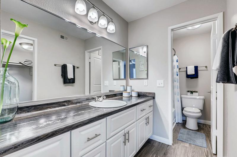 Master Bathroom | Spacious master bathrooms featuring black-fusion counter-tops, wood-style flooring, and large over-sized mirrors.