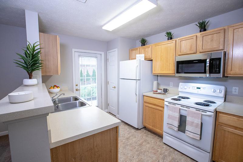 Kitchen | Fully applianced kitchens feature ample cabinetry, a microwave, and dishwasher.