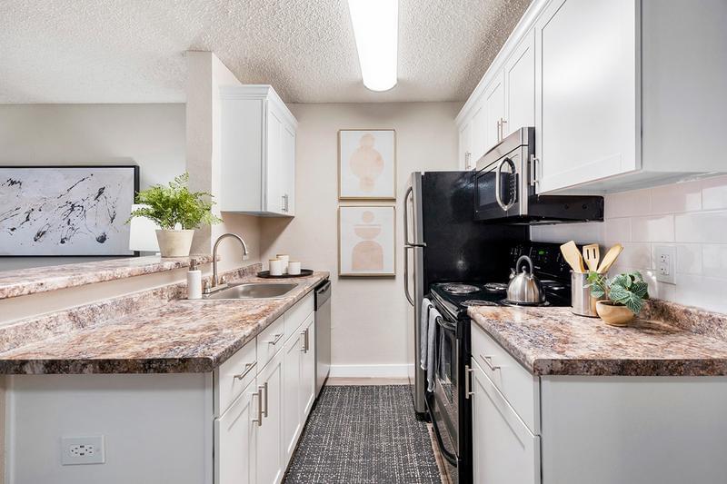 Kitchen | Galley-style kitchens featuring granite-style countertops, wood-style flooring, and stainless steel appliances.