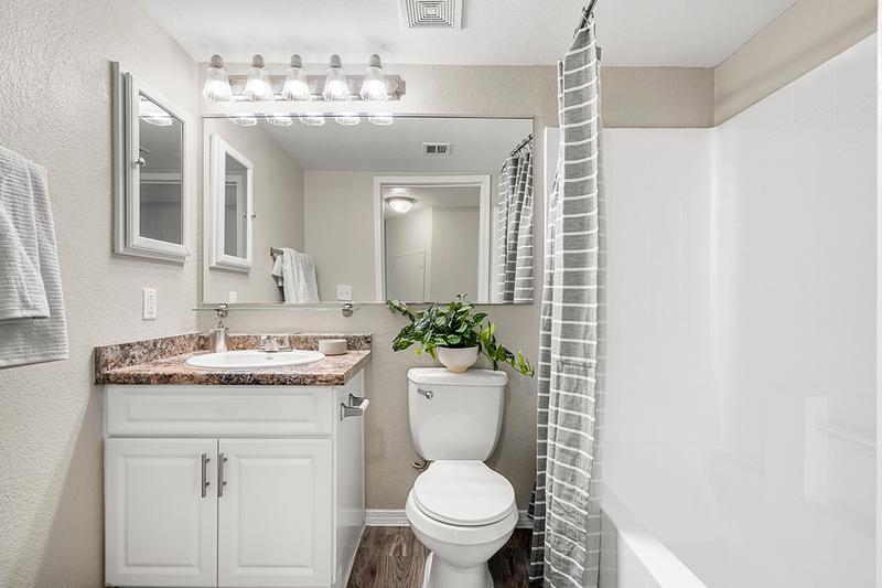 Bathroom | Beautiful remodeled bathrooms featuring wood-style flooring, granite-style counter tops, and large mirrors.