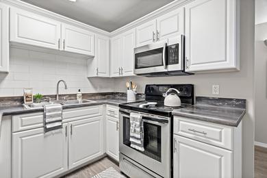 Designer Kitchens with Tile Backsplash | Newly renovated kitchens featuring a large breakfast bar, granite-style counter tops, and ample cabinetry.