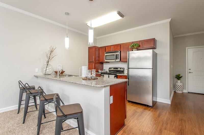 Open Kitchens with Breakfast Bar | Our beautiful one bedroom kitchen layout with cherry wood cabinetry and granite countertops offer a perfect environment for entertaining and relaxing.