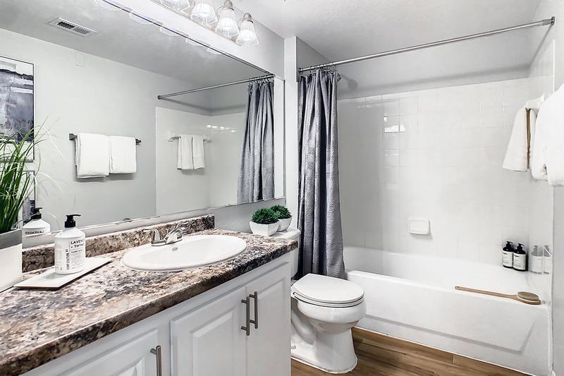 Guest Bathroom | Beautifully renovated bathrooms featuring wood-style flooring and large mirrors.