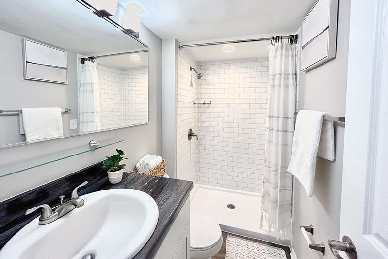 Bathroom | Updated bathrooms featuring black-fusion countertops, wood-style flooring, and large mirrors. 