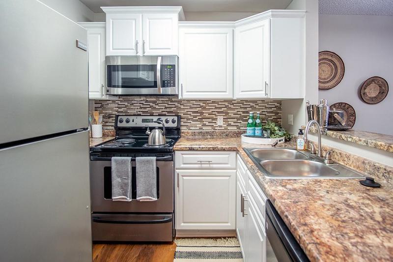 Kitchen | Comfortable kitchens featuring granite-style counter tops, white cabinetry, and wood-style flooring.