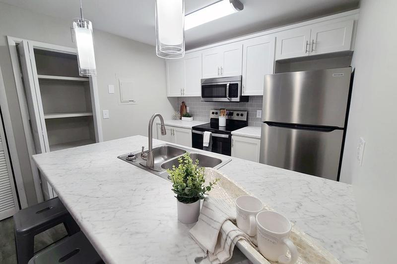 Premium Homes Now Available! | Kitchens feature marble-style countertops, wood-style flooring, a pantry, and stainless steel appliances.