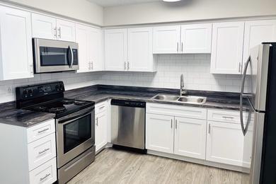 Renovated Kitchens | Newly renovated kitchens featuring black fusion countertops, tiled back splash, wood-style flooring and a breakfast bar. Your kitchen also features full size washer and dryer appliances for your convenience. 