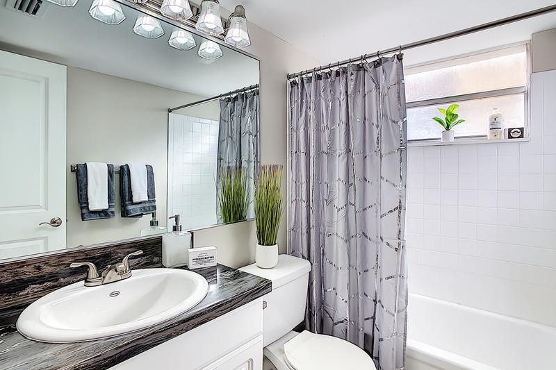 Bathroom | Updated bathrooms featuring white cabinetry, black fusion counter tops, and large mirrors.