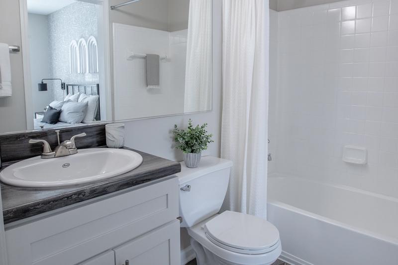 Guest Bathroom | Renovated bathrooms feature black fusion countertops, wood-style flooring and large mirrors.