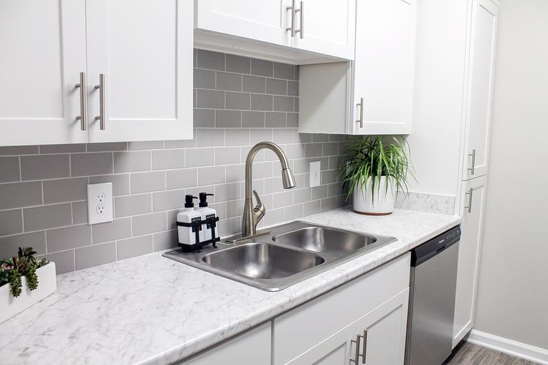 Carrara Marble Countertops | Experience our modern kitchens complete with Cararra marble counters, gray backsplash, and pull down faucet!
