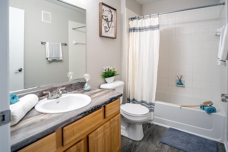 Signature Bathroom | Our renovated apartment homes feature black fusion countertops, and wood-style flooring.