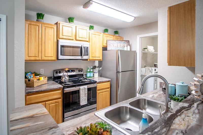 Signature Kitchen | Updated kitchens featuring wood-style flooring, granite-style countertops, and stainless steel appliances available. (In Select Homes)