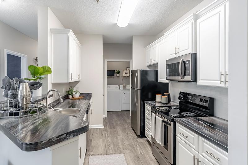 Fully Renovated Kitchens | Our renovated kitchens feature wood-style flooring, white cabinetry, and stainless steel appliances.
