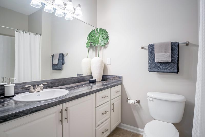 Bathroom | Bathrooms featuring black fusion counter tops, tile flooring, and large mirrors.