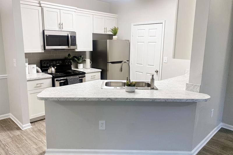 Kitchen Island | Select apartments feature large kitchen islands with pull down faucets and gray tile backsplash.