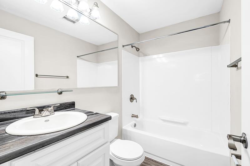 Studio Bathroom | Studio apartments bathrooms feature wood-style flooring and large mirrors. 
