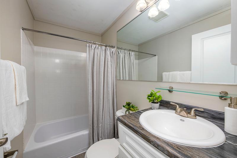 Bathroom | Our newly remodeled bathrooms feature black fusion countertops, wood-style flooring, and a large mirror.