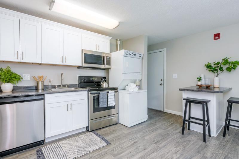 1 Bedroom Modern Style Kitchen | Our newly remodeled apartments feature black fusion countertops, stainless steel appliances, and wood-style flooring. 