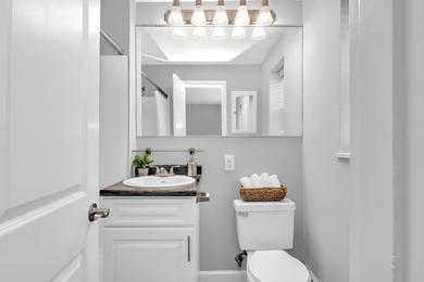 Updated Bathrooms | Newly renovated bathrooms featuring wood-style flooring, black fusion countertops, and large mirrors. 