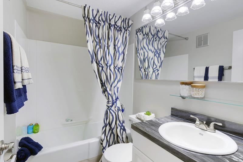 Bathroom | Newly renovated bathrooms featuring granite-style countertops, wood-style flooring, and large mirrors.