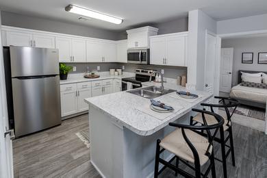 Updated Kitchens | Updated kitchens featuring white Carrera countertops, a breakfast bar, wood-style flooring, and stainless steel appliances.
