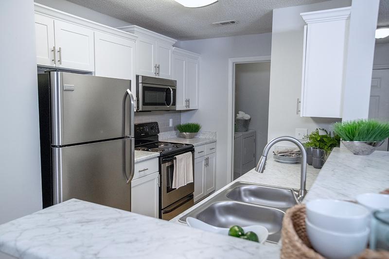 Kitchen | Newly renovated kitchens featuring white marble-style countertops, wood-style flooring, stainless steel appliances, and a breakfast bar.