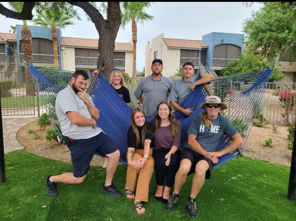 A team picture of Aspen employees sitting in a hammock together. 