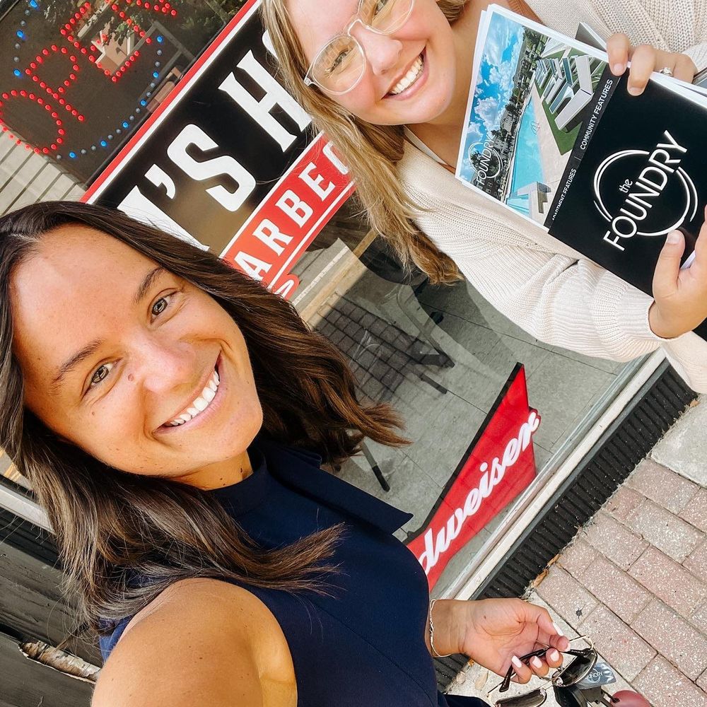 Two people in a selfie holding up marketing materials for The Foundry. 