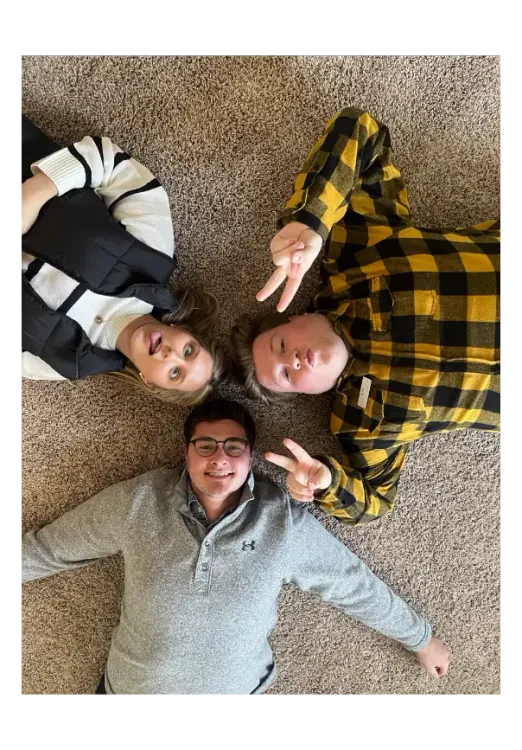Three people lay on the floor below the camera, making funny faces. 