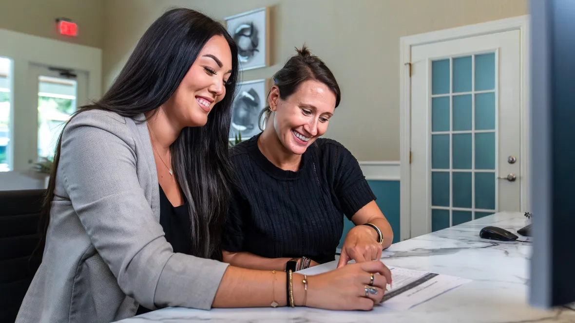 A leasing agent and resident sitting next to each other while resident is signing a lease.