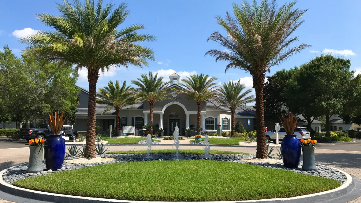 The exterior entry to the leasing center with an imperial circular drive crowned by royal palm trees and an exquisite, bubbling water feature. 
