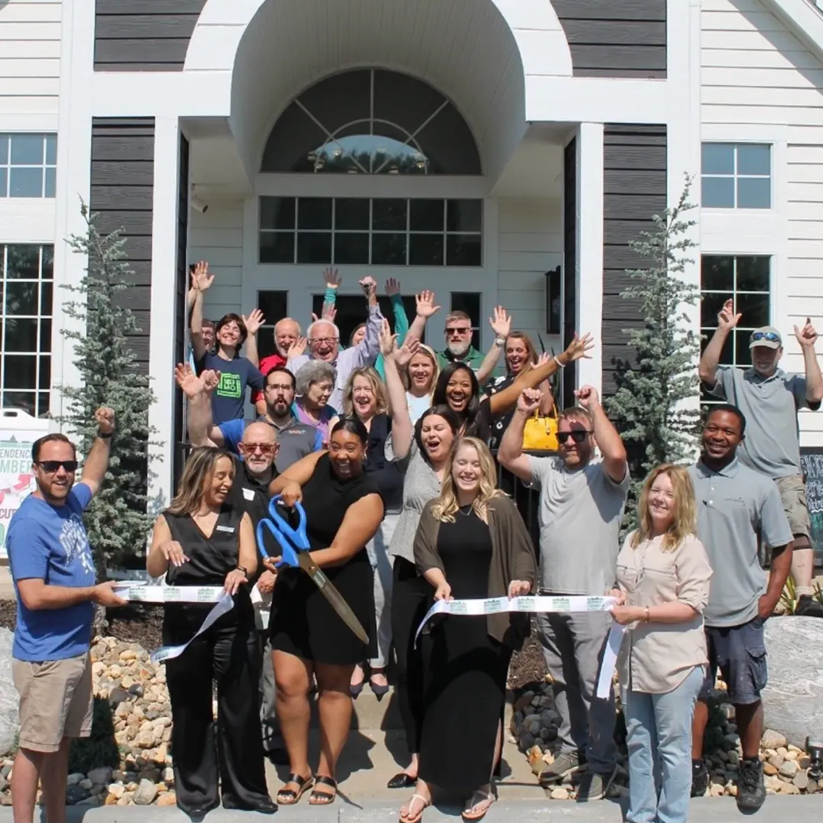A group of people at the ribbon cutting for a new property. 
