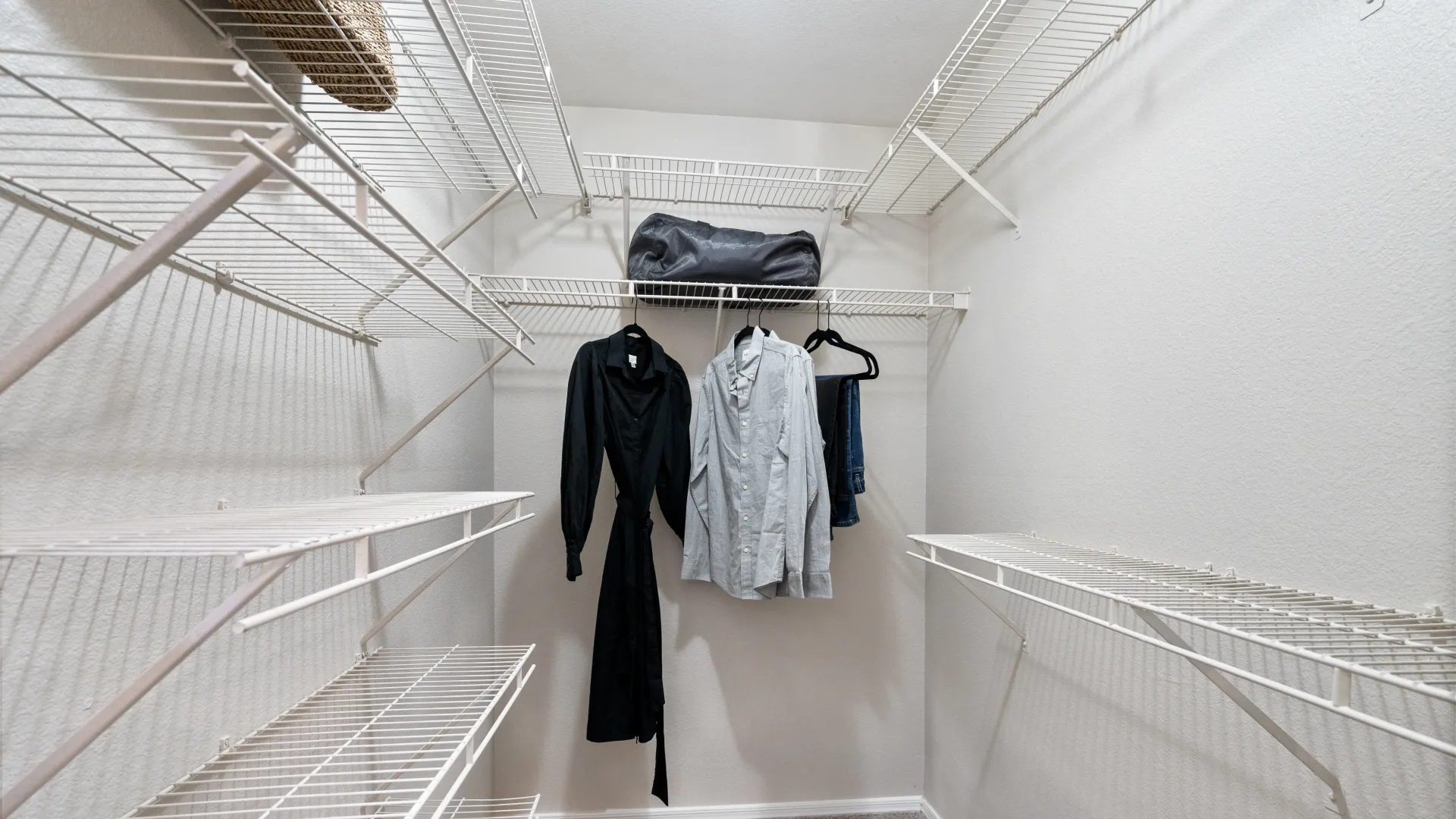 A spacious walk-in closet with built-in shelving, hanging rods, and neatly arranged clothing, offering ample storage and organization space.