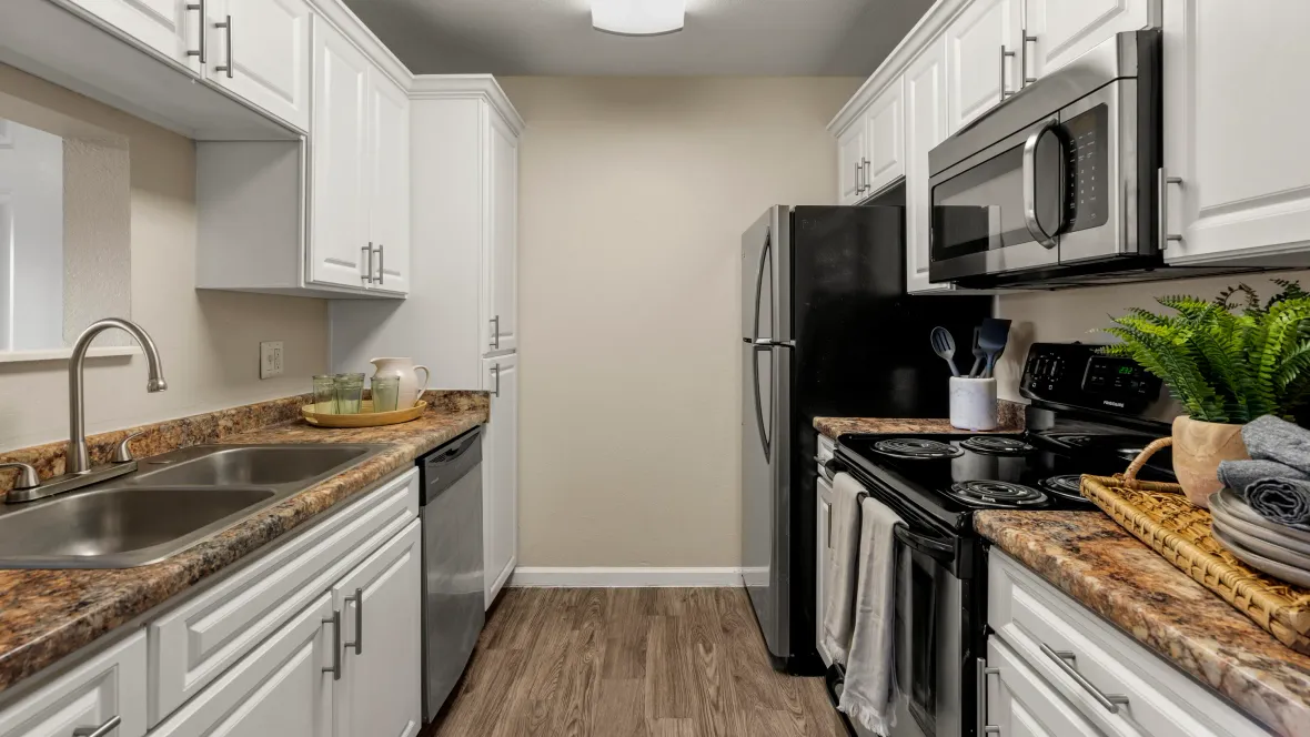 Elegant galley kitchen with stainless steel appliances including dishwasher, refrigerator, microwave and oven – complete with large built-in pantry. 