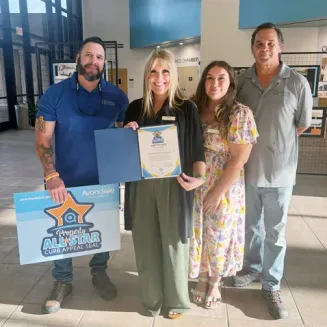 Sedona Peaks team holding Avondale's Property All-Star Curb Appeal Award and certificate inside a civic building, celebrating a historic recognition for the multifamily community.